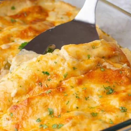 White Chicken Enchiladas Cheesy chicken casserole in a glass dish with a spoon.