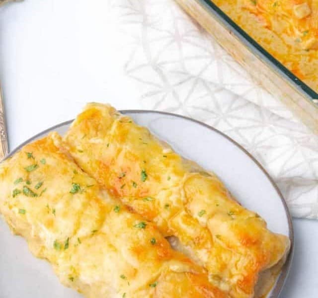 Cheesy chicken enchiladas on a plate with a fork.