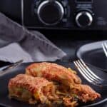 Crock pot stuffed cabbage rolls recipe cooked set on a black plate with a fork and knife