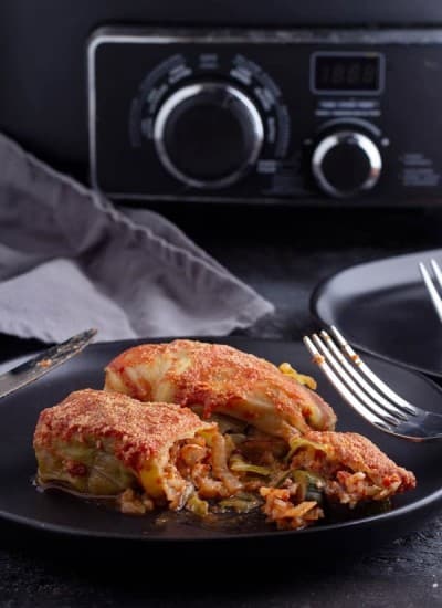 Crock pot stuffed cabbage rolls recipe cooked set on a black plate with a fork and knife