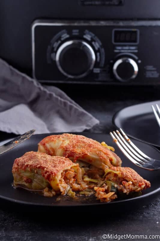 Crock pot stuffed cabbage rolls recipe cooked set on a black plate with a fork and knife