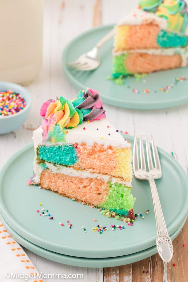 slice of rainbow cake on a plate with a fork