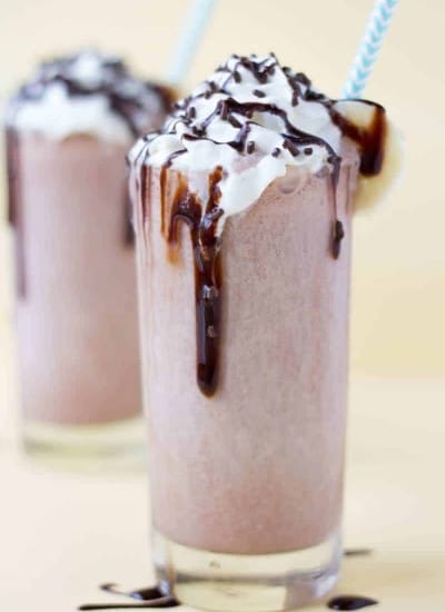 Chocolate Banana Milkshake with whipped cream drizzled with chocolate syrup and chocolate shavings