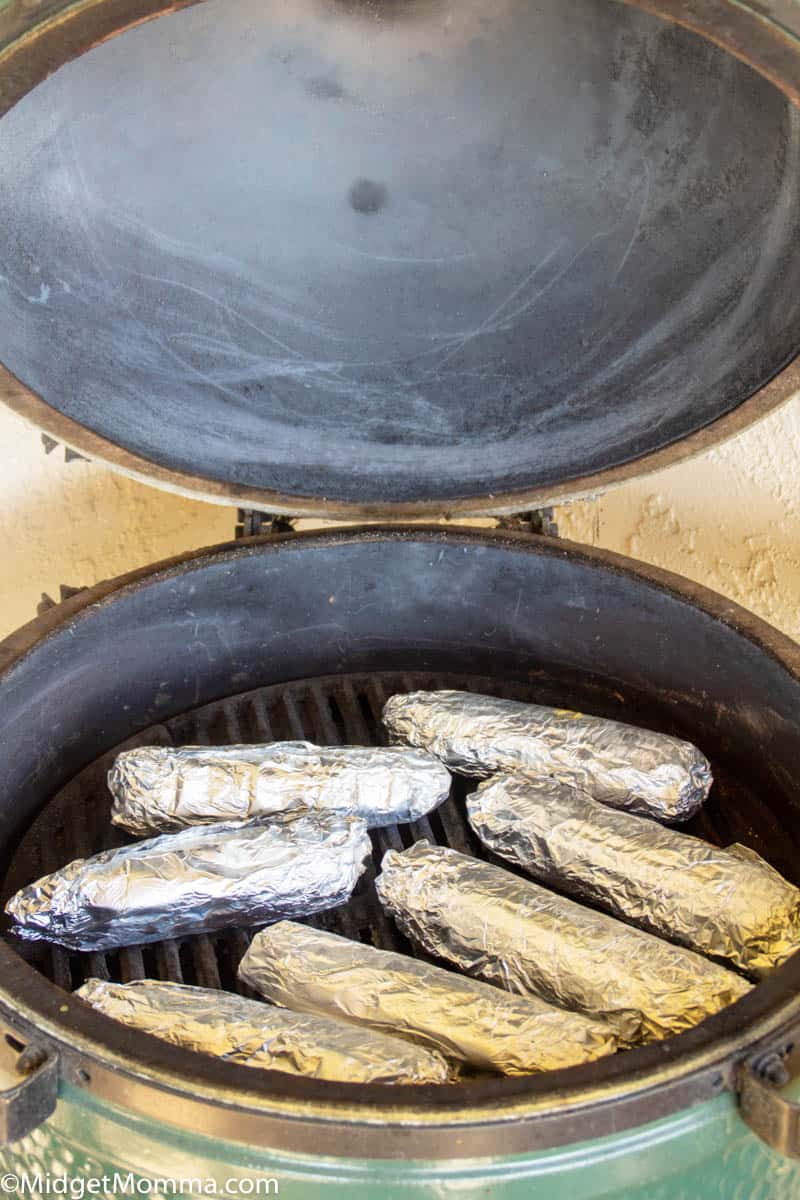 Corn wrapped in tin foil cooking on the grill