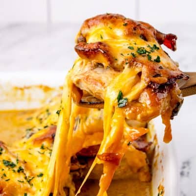 cheesy Alice springs chicken being take out of the baking dish with a spatula