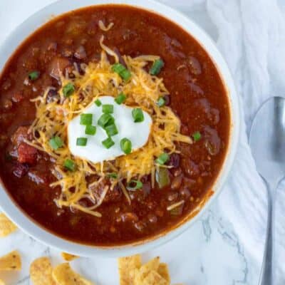 How to make crockpot chili low carb - chili in a bowl on the counter topped with green onions, cheddar cheese and sour cream