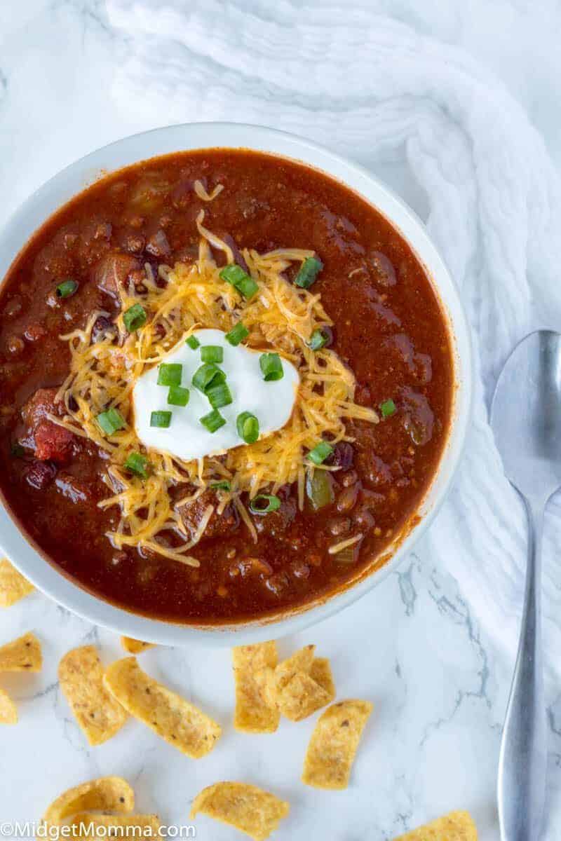 How to make crockpot chili low carb - chili in a bowl on the counter topped with green onions, cheddar cheese and sour cream