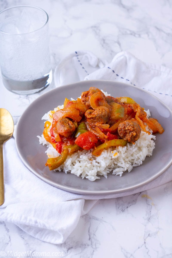 sausage and peppers on top of rice on a plate 