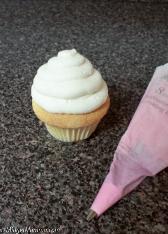 how to make ghost cupcakes - cupcake with white frosting and piping bag with black frosting