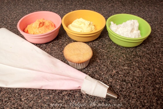 Candy Corn cupcake ingredients, 3 bowls of homemade frosting. Each bowl died a different color - white frosting, orange frosting and yellow frosting