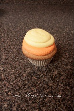 Candy corn cup cake step 2 - swirl of yellow frosting on top of orange swirl to make the candy corn shape with the frosting