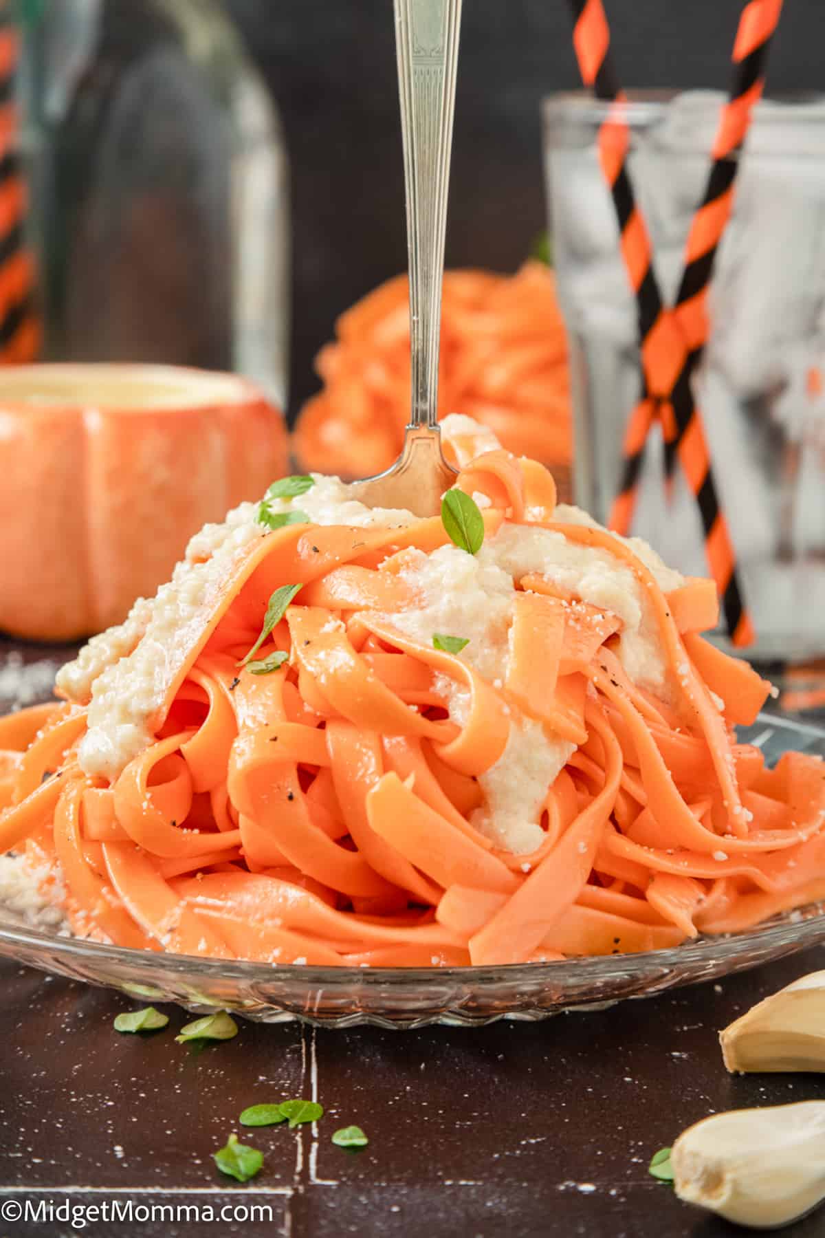 orange halloween pasta topped with garlic cream sauce