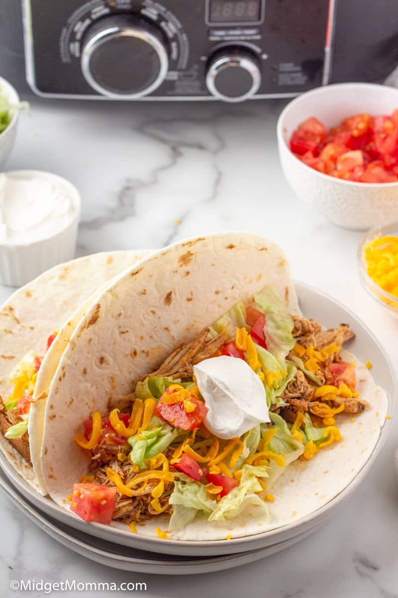 Open chicken taco in soft taco shell with lettuce, tomato, cheese and sour cream 