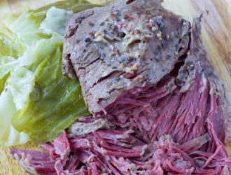 Sliced corned beef and cabbage on a cutting board.