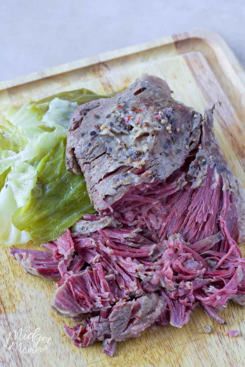 Sliced corned beef and cabbage on a cutting board.