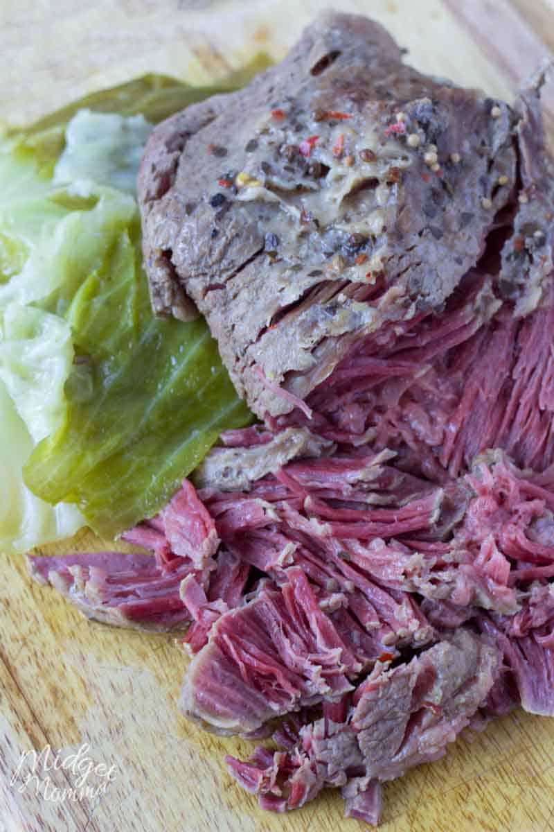 Sliced corned beef and cabbage on a cutting board.