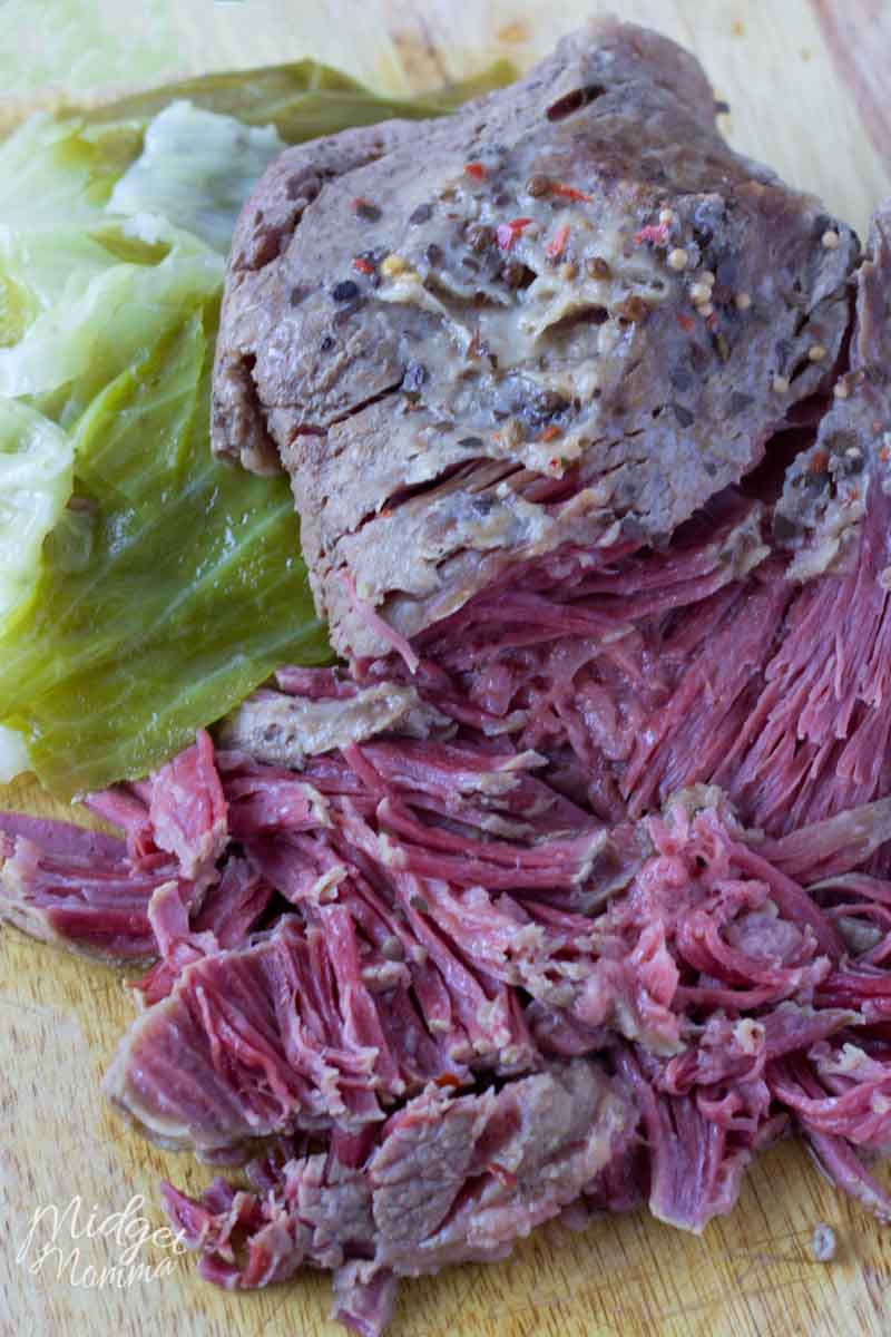 Sliced corned beef and cabbage on a cutting board.