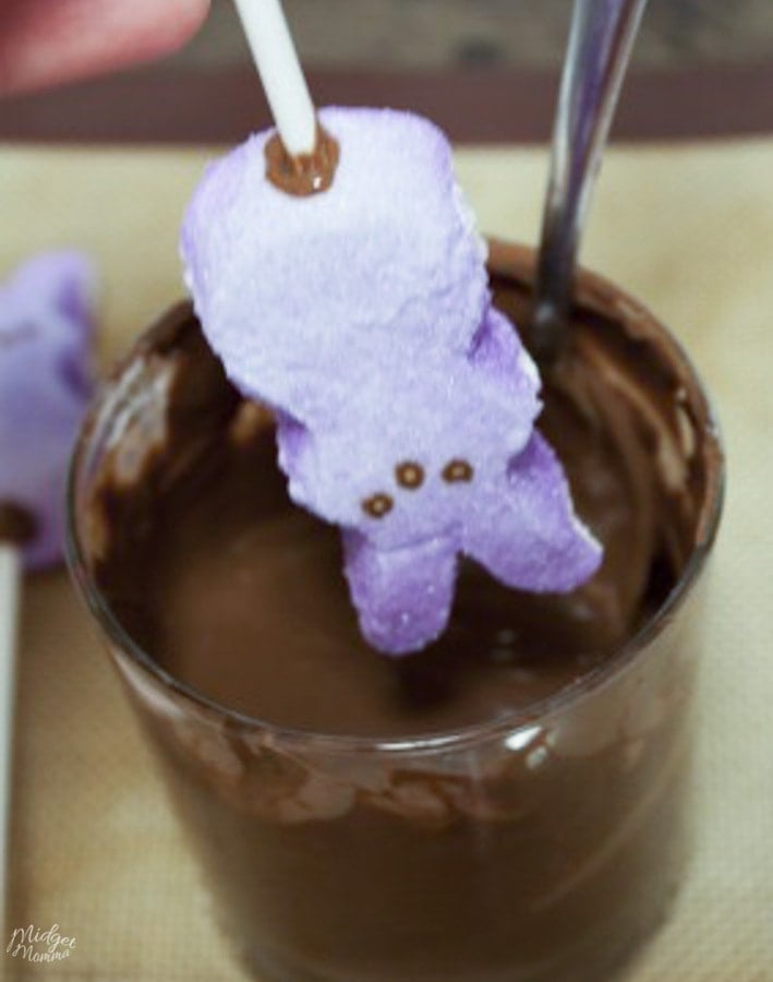 dippping marshmallow peeps in to a bowl of chocolate to make chocolate covered peeps
