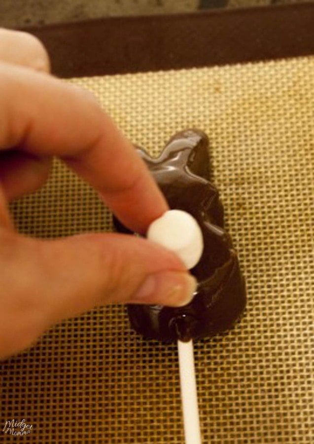 mini marshmallow being put on the backside of a chocolate covered marshmallow peep bunny