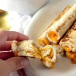 cheesy grilled cheese roll up broken in half to see cheese ozzing from inside the grilled cheese roll up