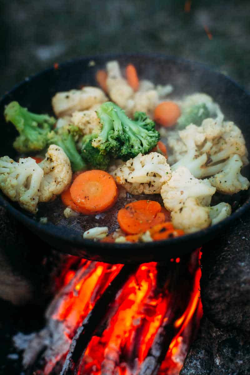 Cauliflower, broccoli and carrot in a pan. Cooking on an open fire. Outdoor food. Grilled vegetables. Food on a camping trip