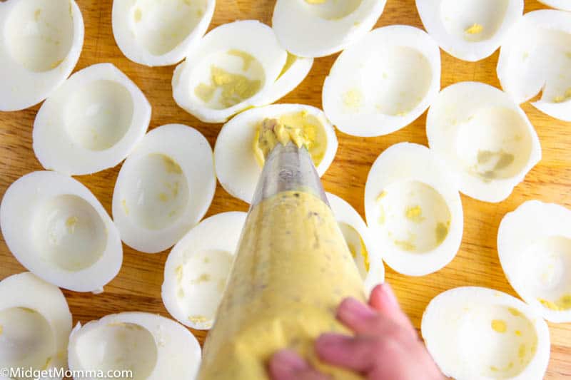 piping bag with bacon deviled egg mixture piping mixture into egg white halves