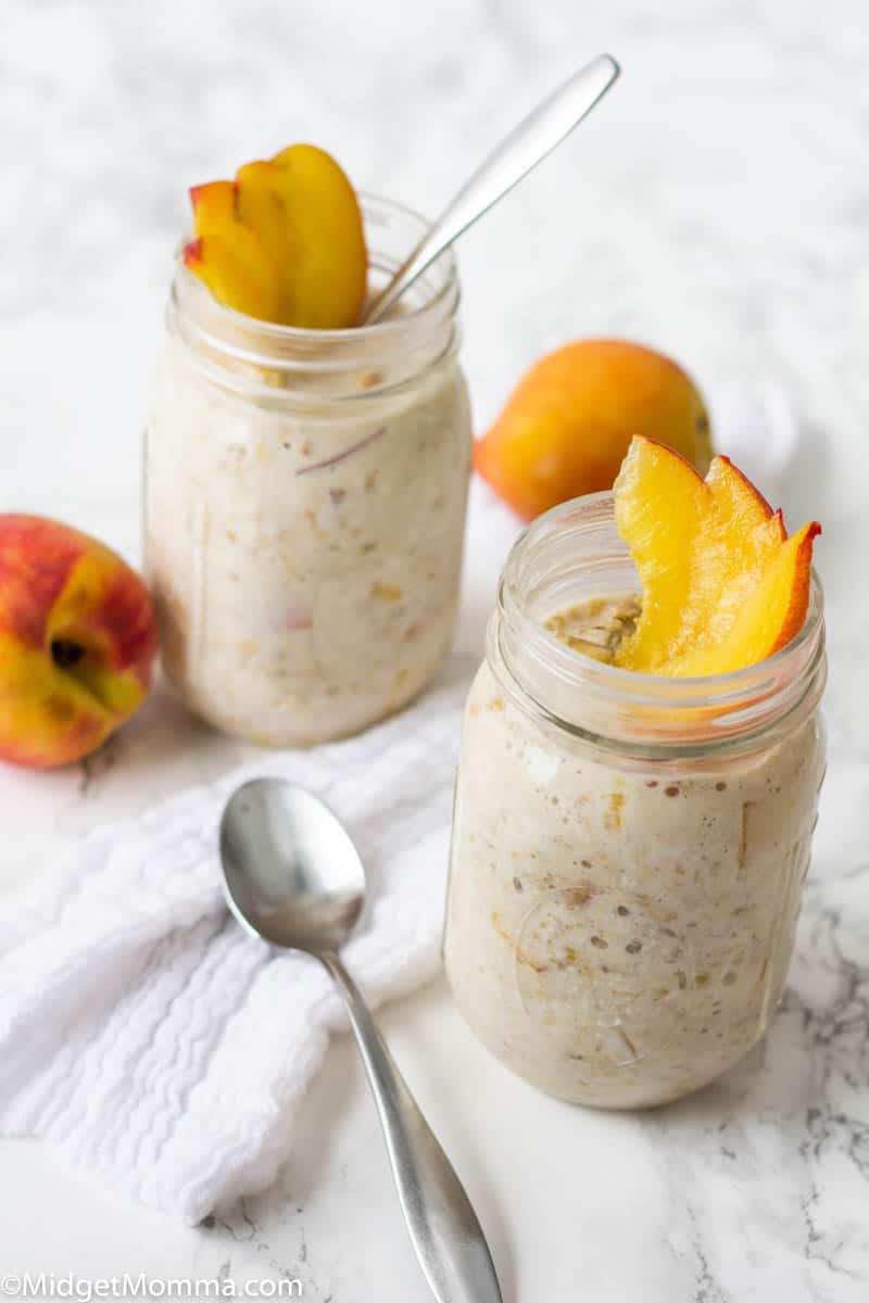 2 mason jars with peach overnight oats topped with fresh peaches