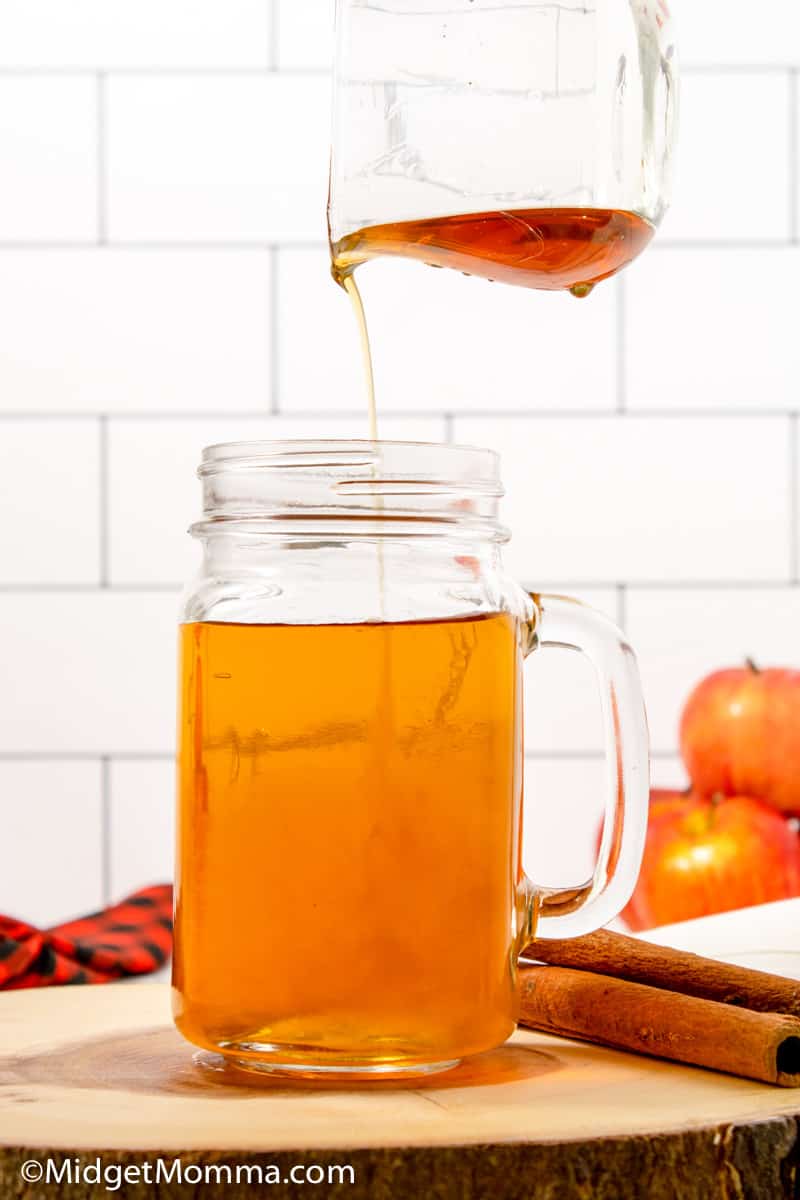 cinnamon dolce syrup being poured into a glass of apple juice