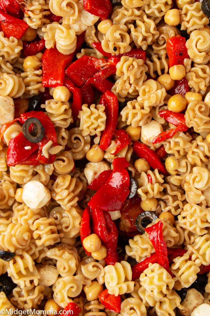 Roasted Red Pepper Pasta Salad recipe in a glass bowl with wooden spoons