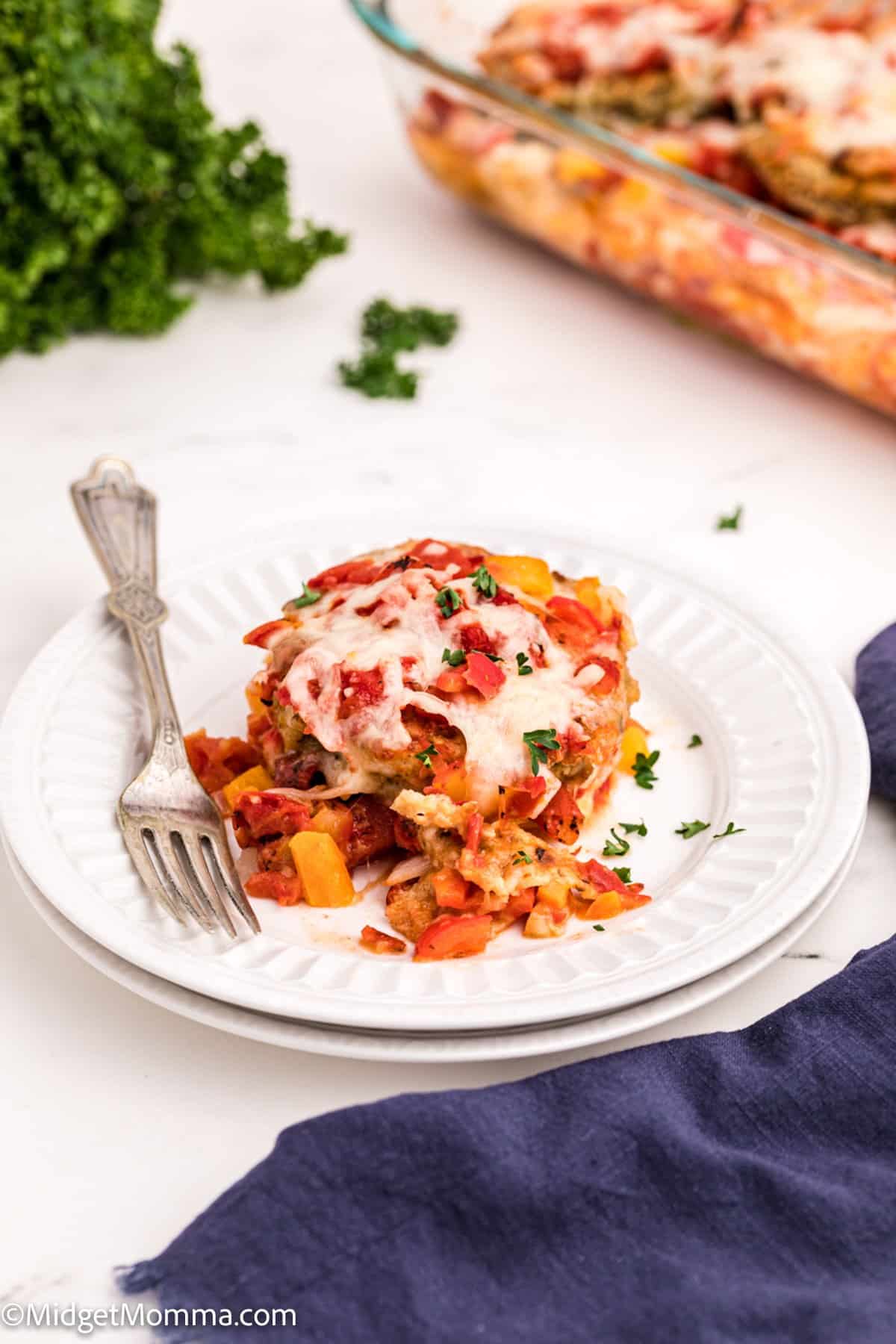 Baked Eggplant Parmesan on a white plate with a fork