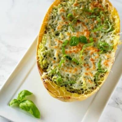 This Chicken Pesto Spaghetti Squash is an oven baked spaghetti squash recipe that is bursting with flavor. Chicken and Pesto combine for a flavorful spaghetti squash recipe that everyone will enjoy. #Chicken #SpaghettiSquash #Pesto #BakedSpaghettiSquash #Dinner #SpaghettiSquashRecipe #ChickenSpaghettiSquash