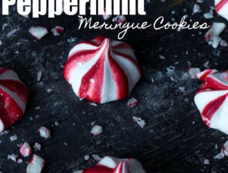A few of fresh made peppermint meringue cookies on a black baking sheet