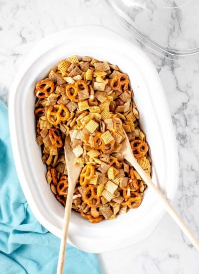 white crockpot filled with the ingredients to make slow cooker chex mix