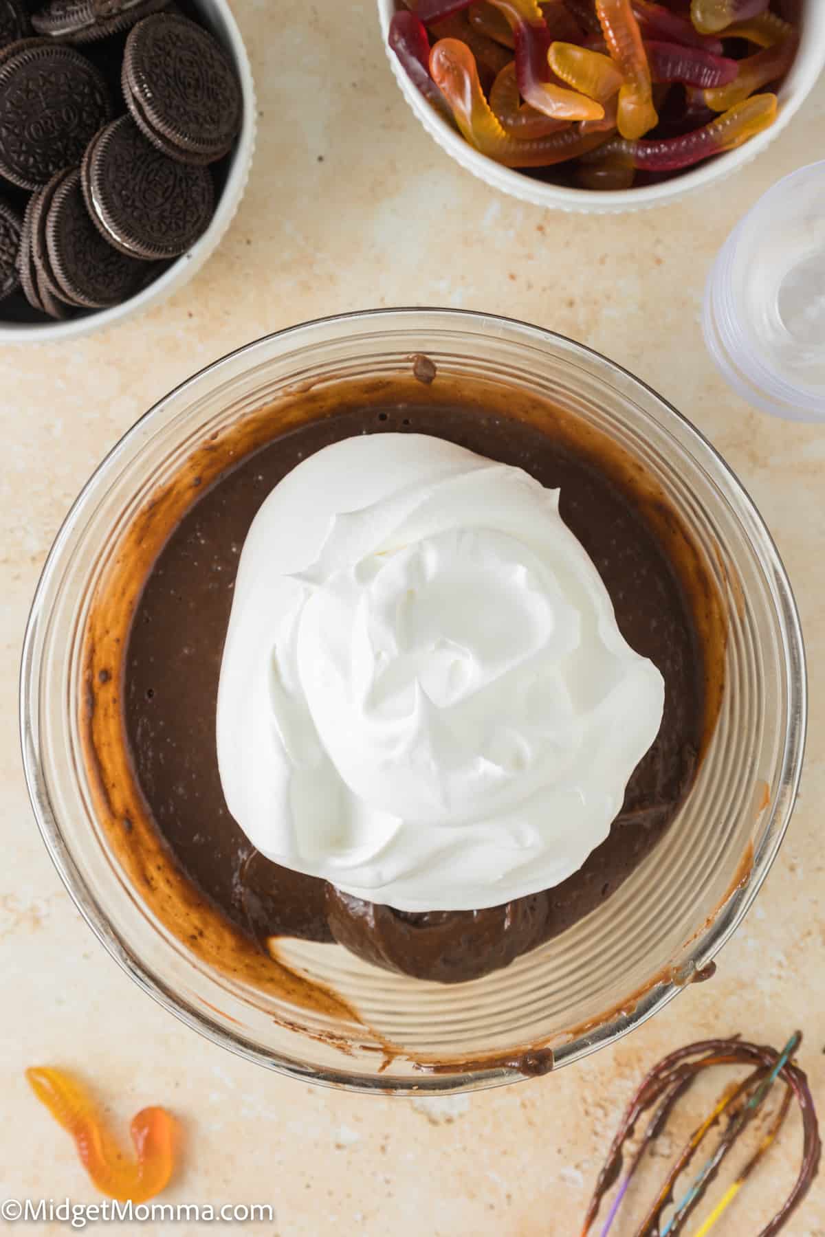 cool whip topping being added to mixed chocolate pudding in a bowl
