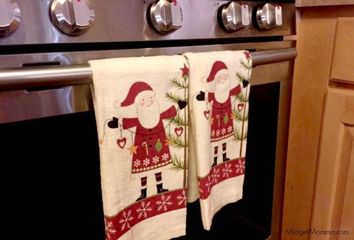 Christmas towels hanging from a bar on a stove.
