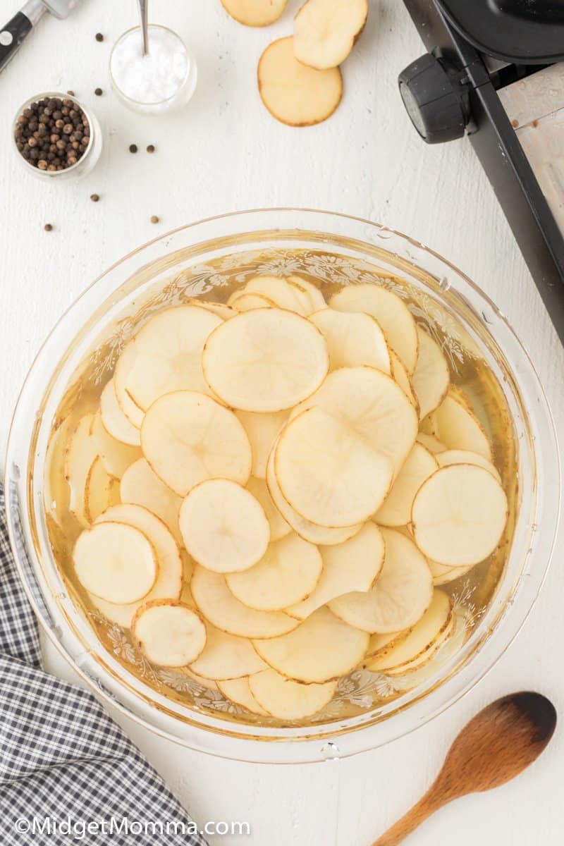 sliced potatoes soaking in a bowl of water