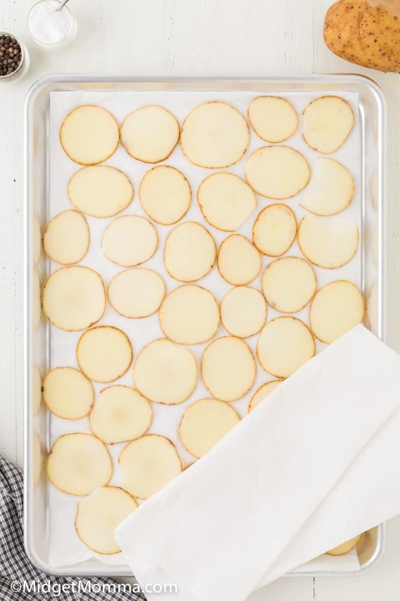 sliced potatoes drying on a baking sheet