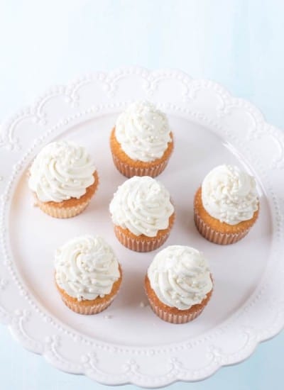 the best vanilla cupcakes topped with vanilla buttercream on a white platter