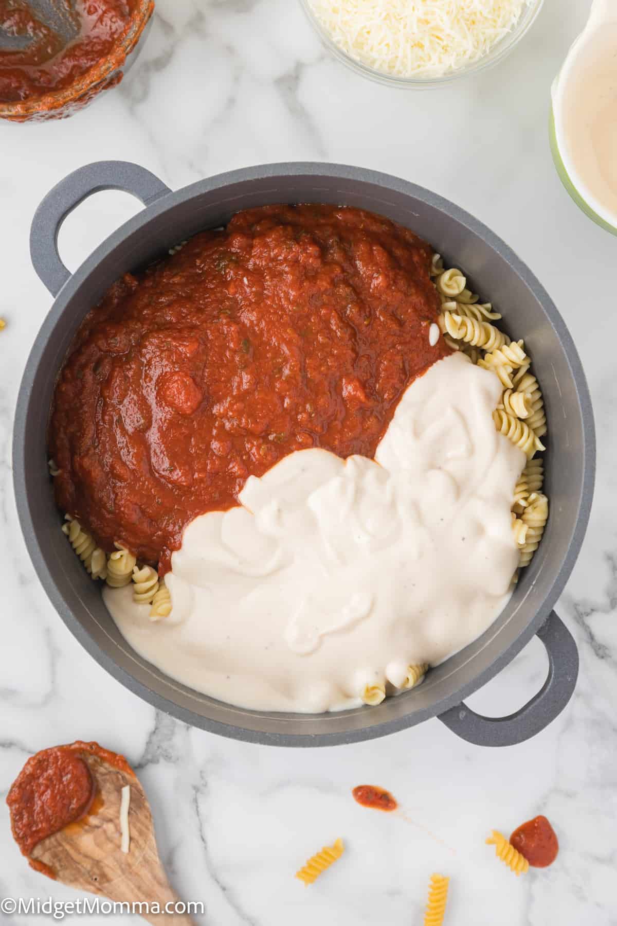 cooked pasta in a pot with marinara sauce and alfredo sauce