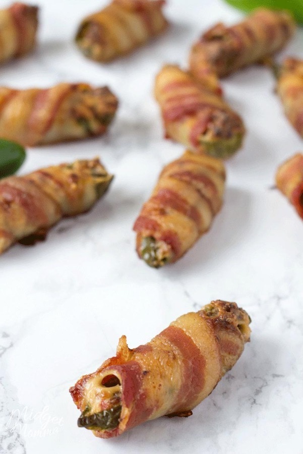 These easy stuffed bacon wrapped Jalapeno poppers are the perfect party appetizer. These oven baked Jalapeno poppers are full of flavor. With a mixture of cream cheese and sausage stuffed inside Jalapeno peppers then wrapped in bacon and baked in the oven these are the perfect appetizer to make! #Jalapeno #JalapenoPoppers #JalapenoPopper #JalapenoAppetizer bacon wrapped jalapenos cooked in the oven.