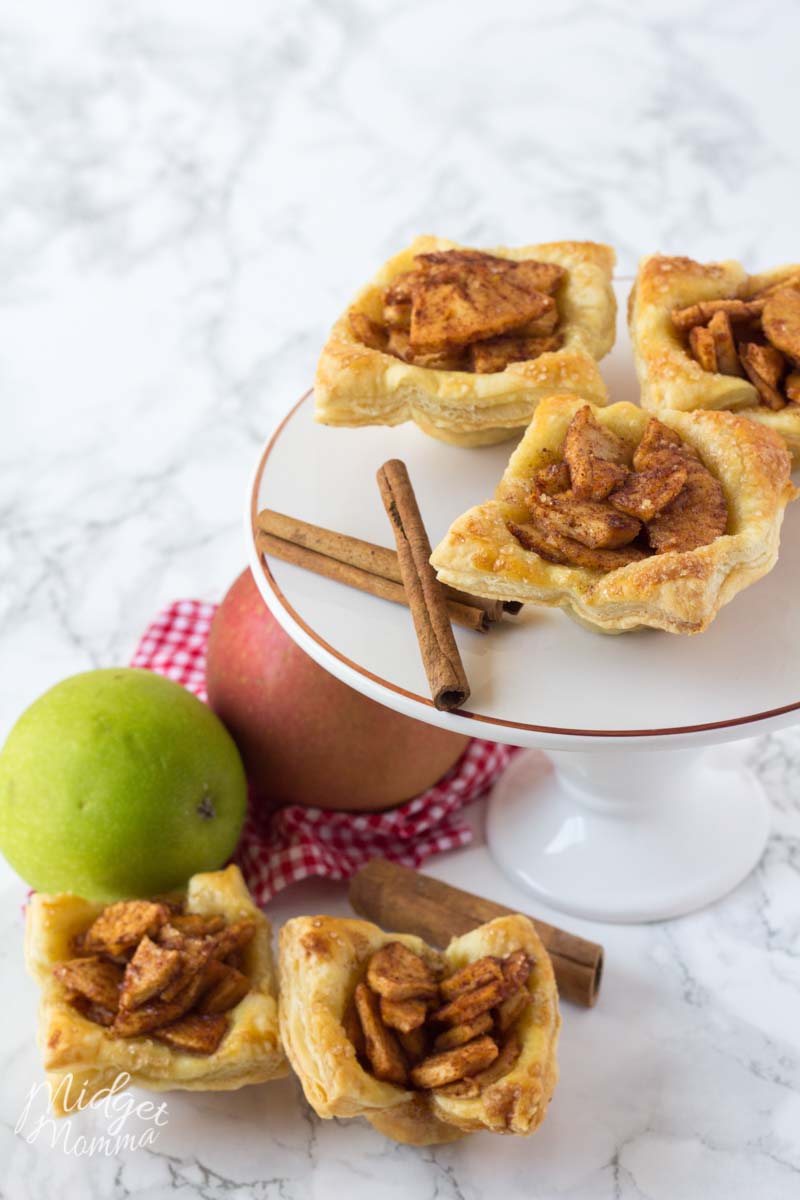 apple puff pastry - 3 set on a cake pan and 2 next to it in the perfect apple pie dessert display