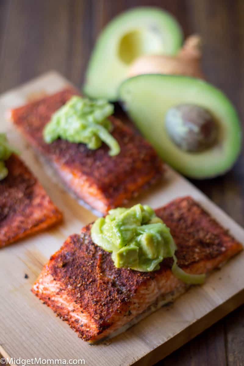 grilled salmon seasoned with spices and topped with avocado onion salsa on a cutting board