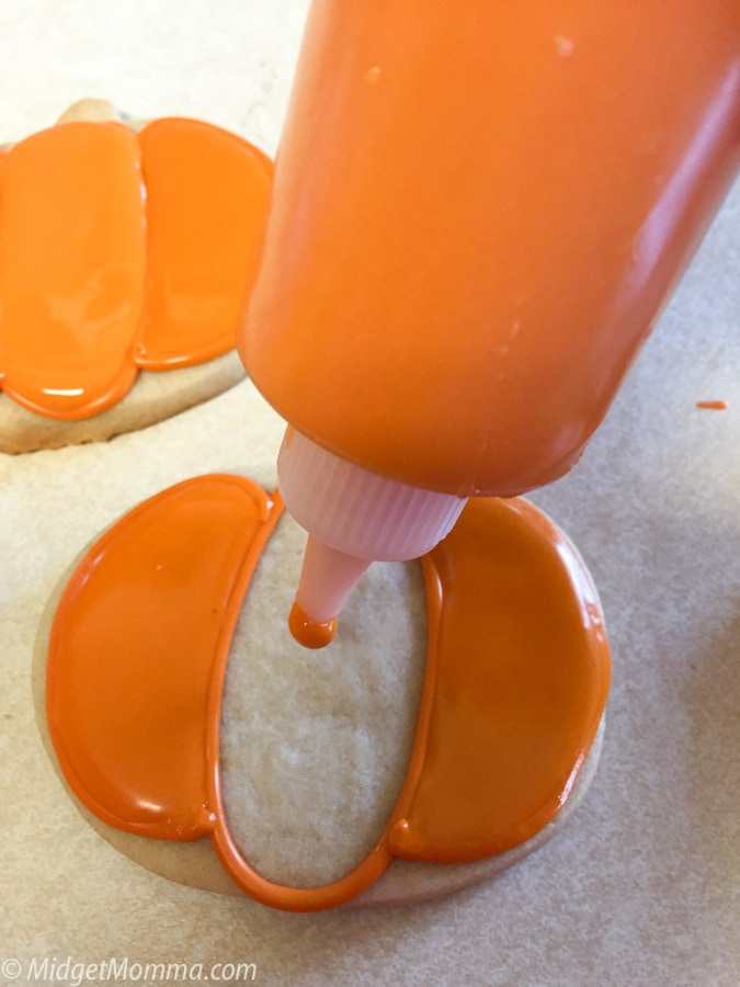 Frosting pumpkin cookies with royal icing