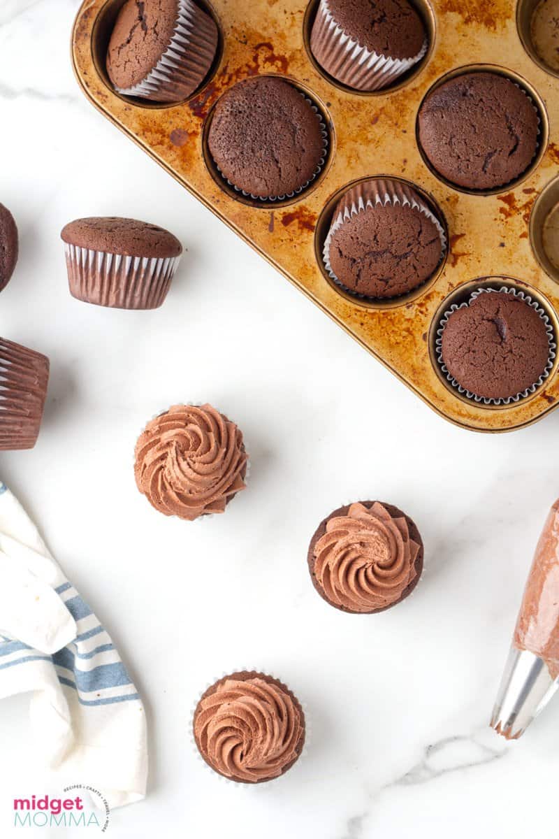 over head shot of chocolate cupckakes with frosting and a few cupcakes in the cupcake tray