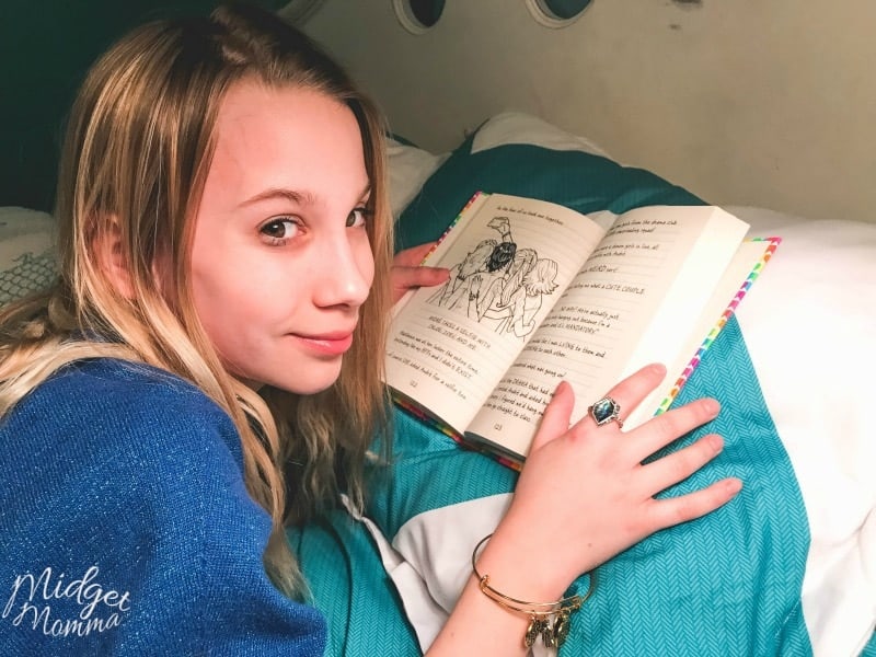 Teenage girl laying on her bed reading.