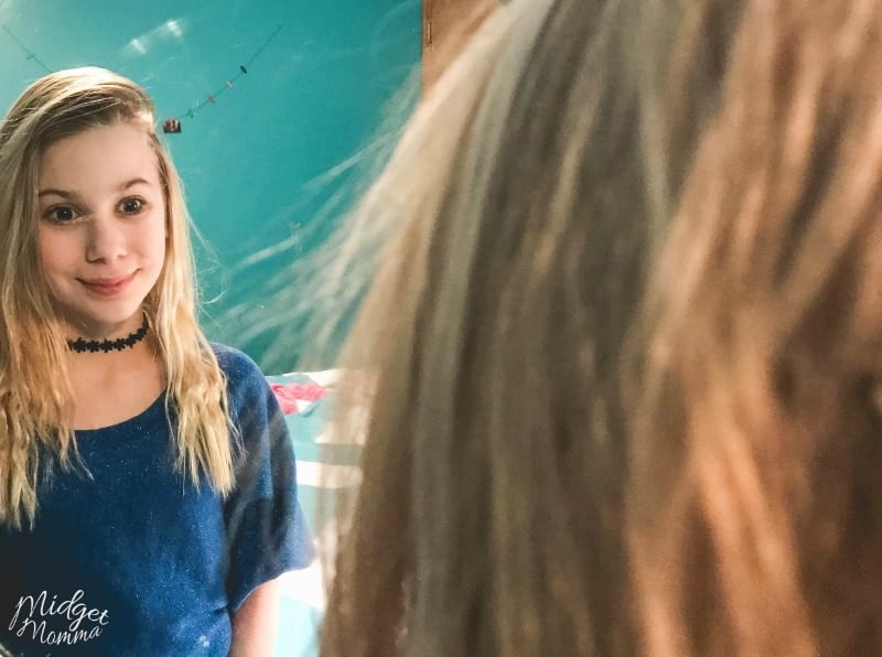 Teenage girl smiling at her reflection in the mirror.