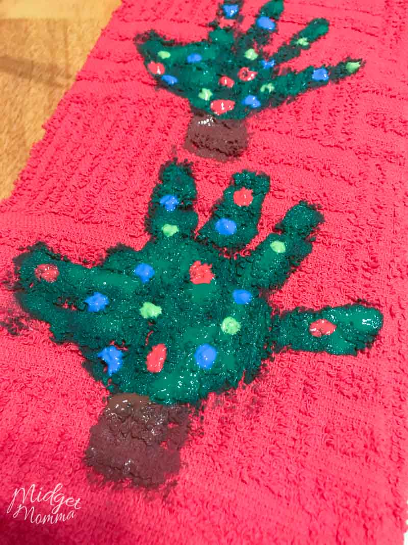 kids handprint christmas tree craft kitchen towel with green christmas tree made with handprint, with painted on ornaments on a red kitchen tea towel