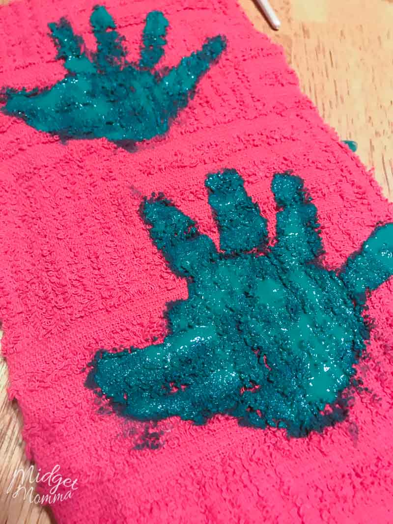 kids handprint in green paint on a red tea towel