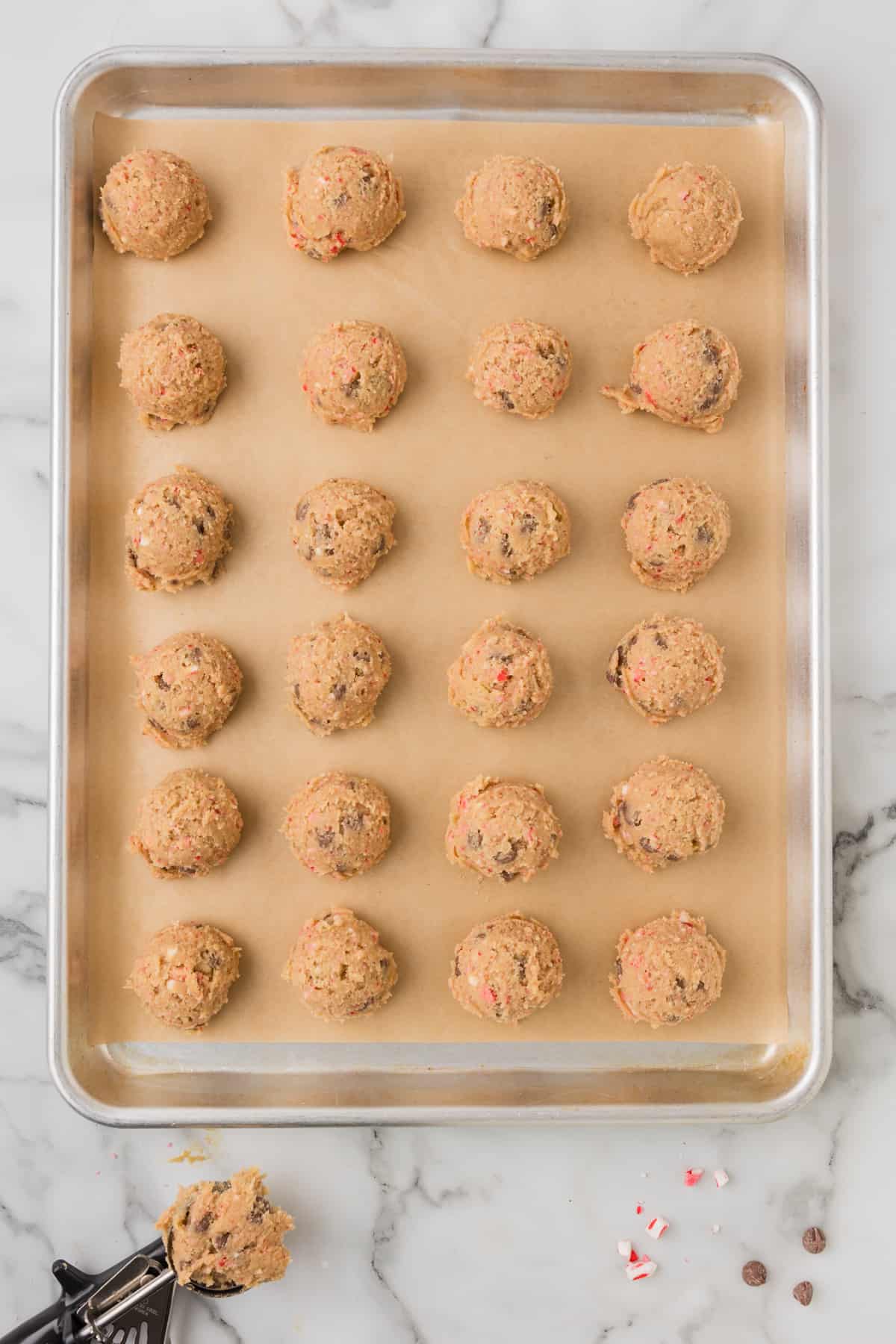 Peppermint Chocolate chip cookie dough on a baking sheet with a spatula.