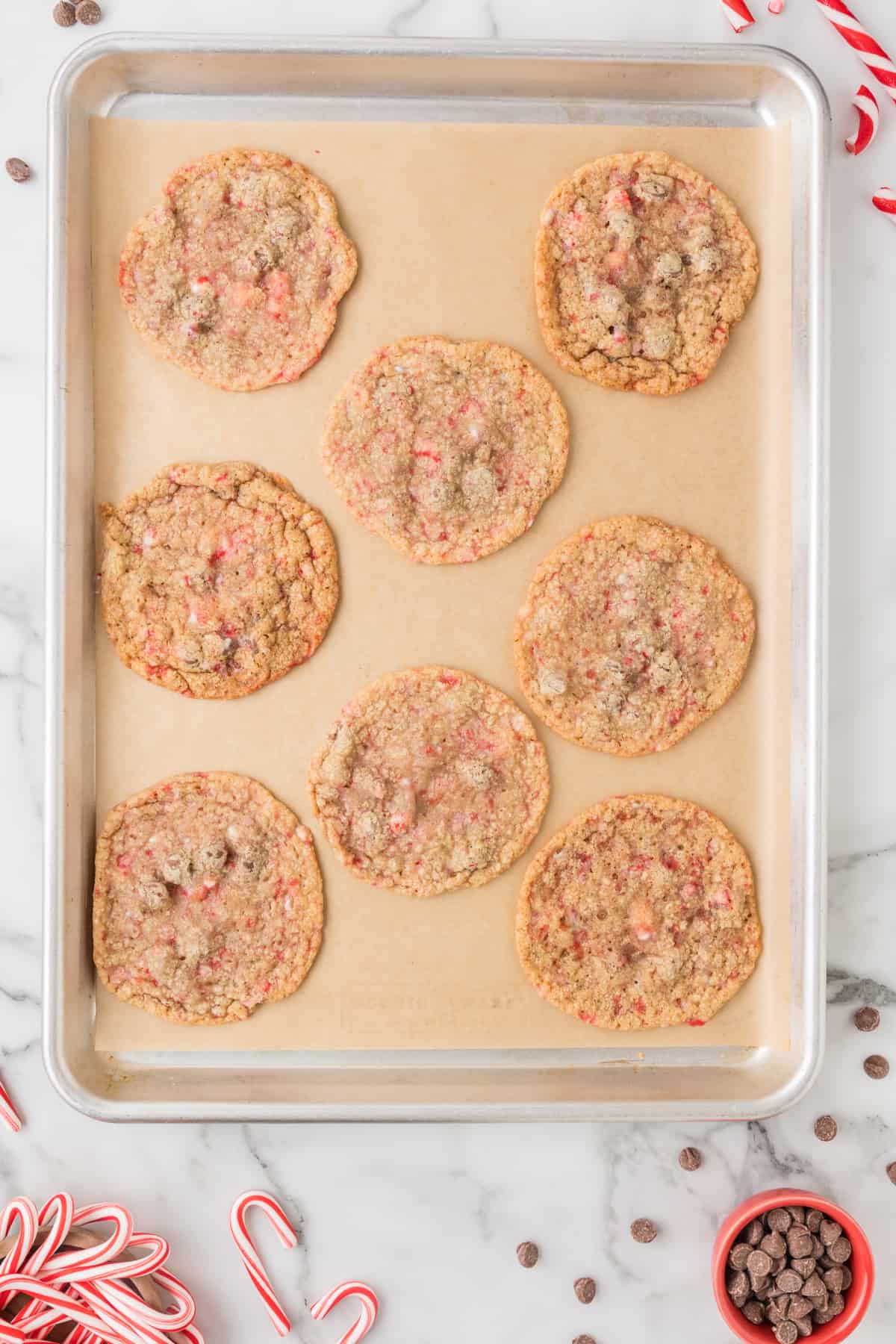 peppermint chocolate chip cookies on a baking sheet with candy canes.